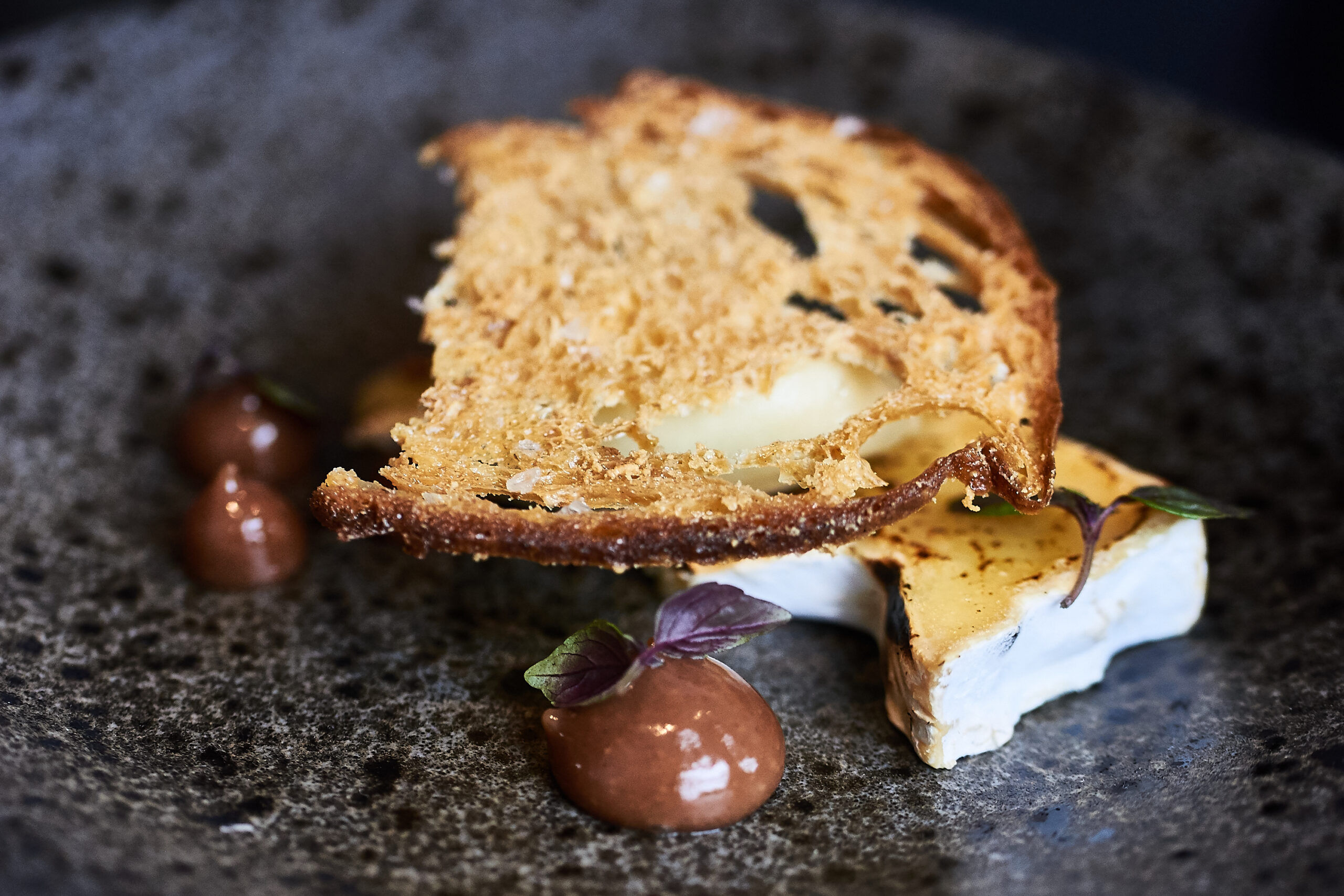 Cheese with sourdough served on a black plate at etch. restaurant.