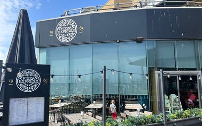 the dark exterior of Pizza Express restaurant on Brighton marina. The big menu board situated in front and green plants framing the alfresco area
