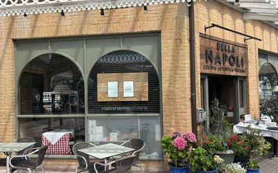 the brick building on Brighton Marina which is Bella Napoli Italian restaurant and cafe. Tables and alfresco seating with terrace plant pots