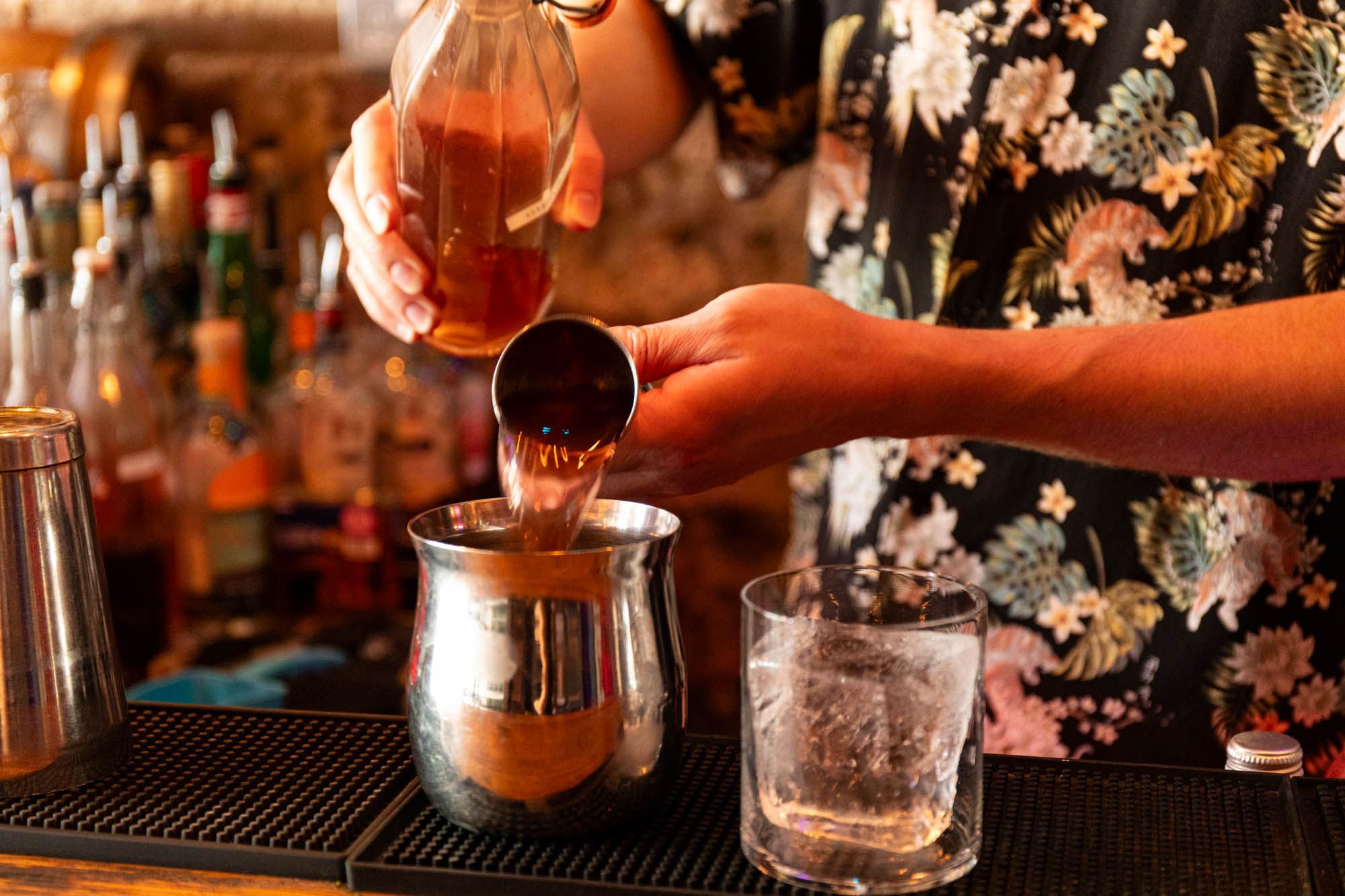 person sipping alcoholic drink inside the metal cup as a part of preparation for making cocktails