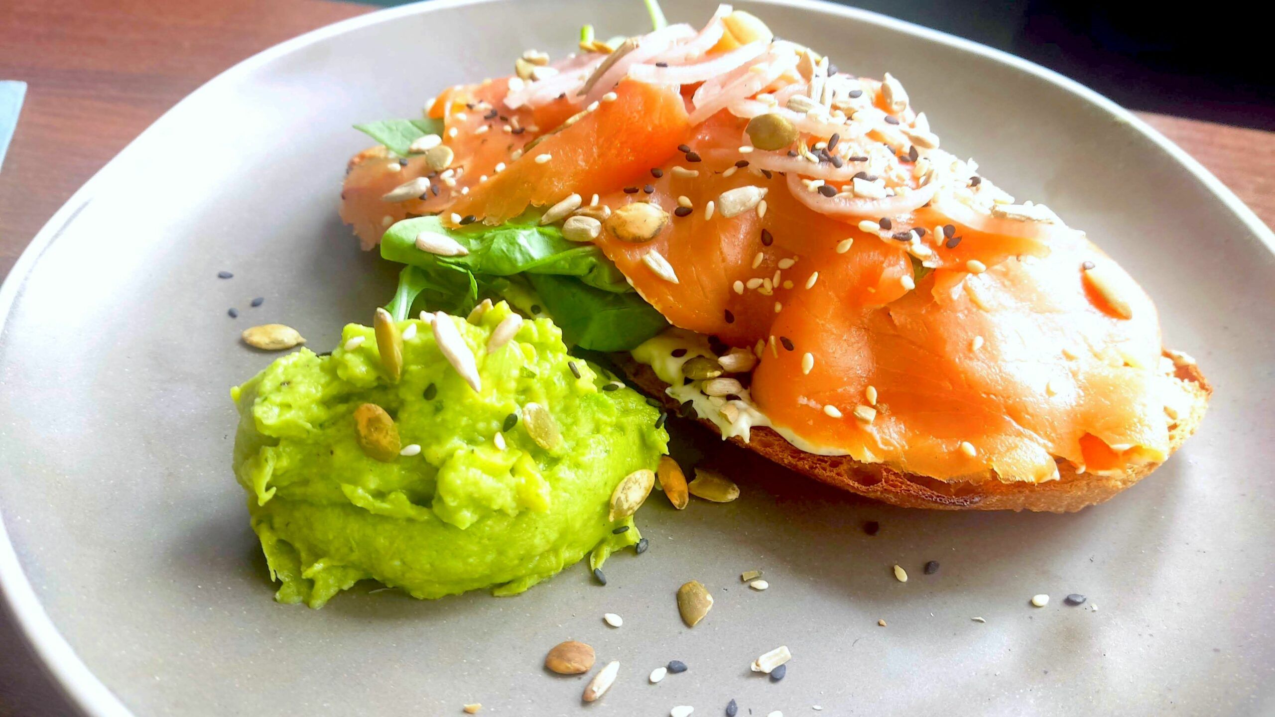Brunch and Cocktails at Baked Hove. Salmon toast with avocado served on white plate