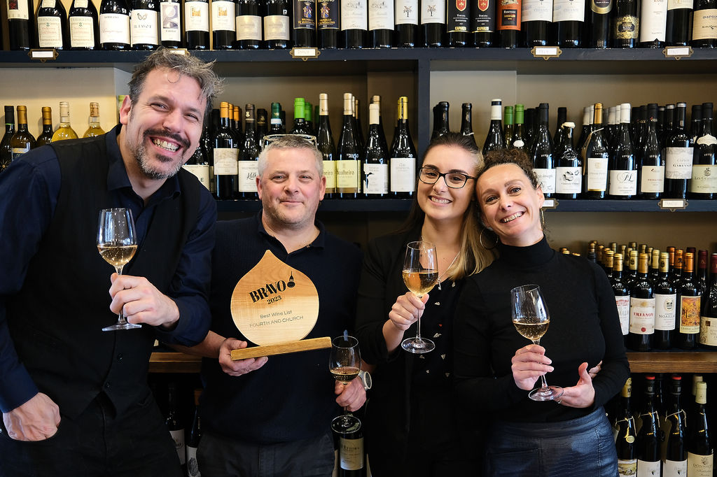 Wine Tasting Brighton. Anna, Paul and the team gearing up for one of their Brighton wine tasting events. The backdrop is a wall of wine, displaying their shop front located on Church Road in Hove. Fourth and Church also have noteworthy wine lists. Fourth and Church won the BRAVO 2023 best wine list in Brighton