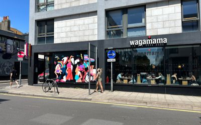 Wagamam restaurant in Brighton. Pictured the front of the building with pedestrians walking by, a blue sky backdrop
