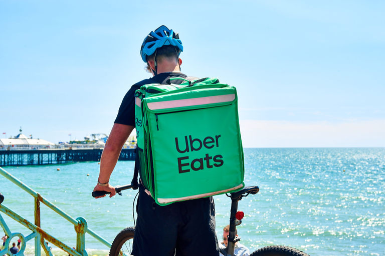 Uber Eats takeaway delivery cyclist on Brighton beach on a sunny day. New Years Eve Brighton