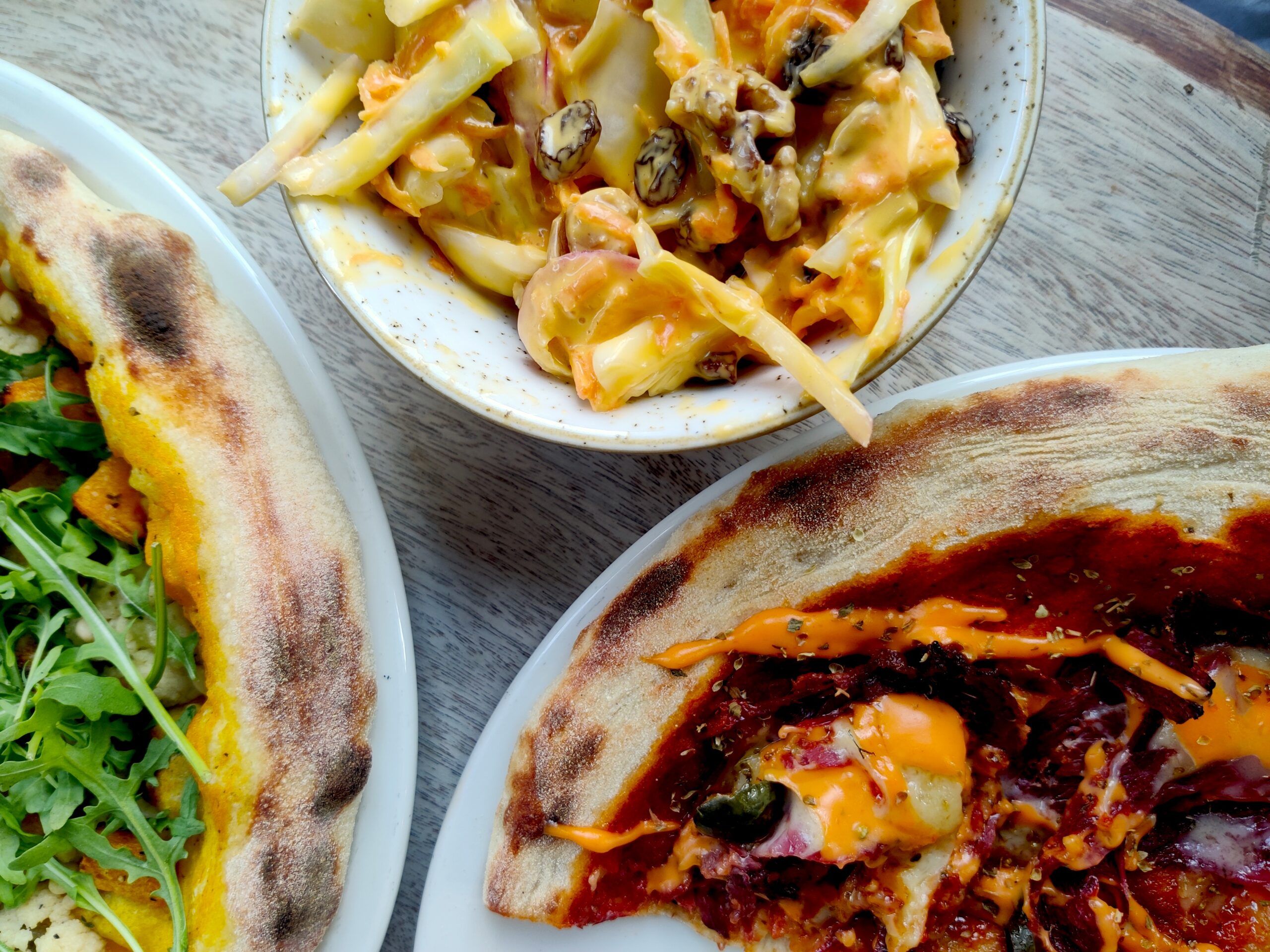 Over head shot of two pizzas and coleslaw salad. 