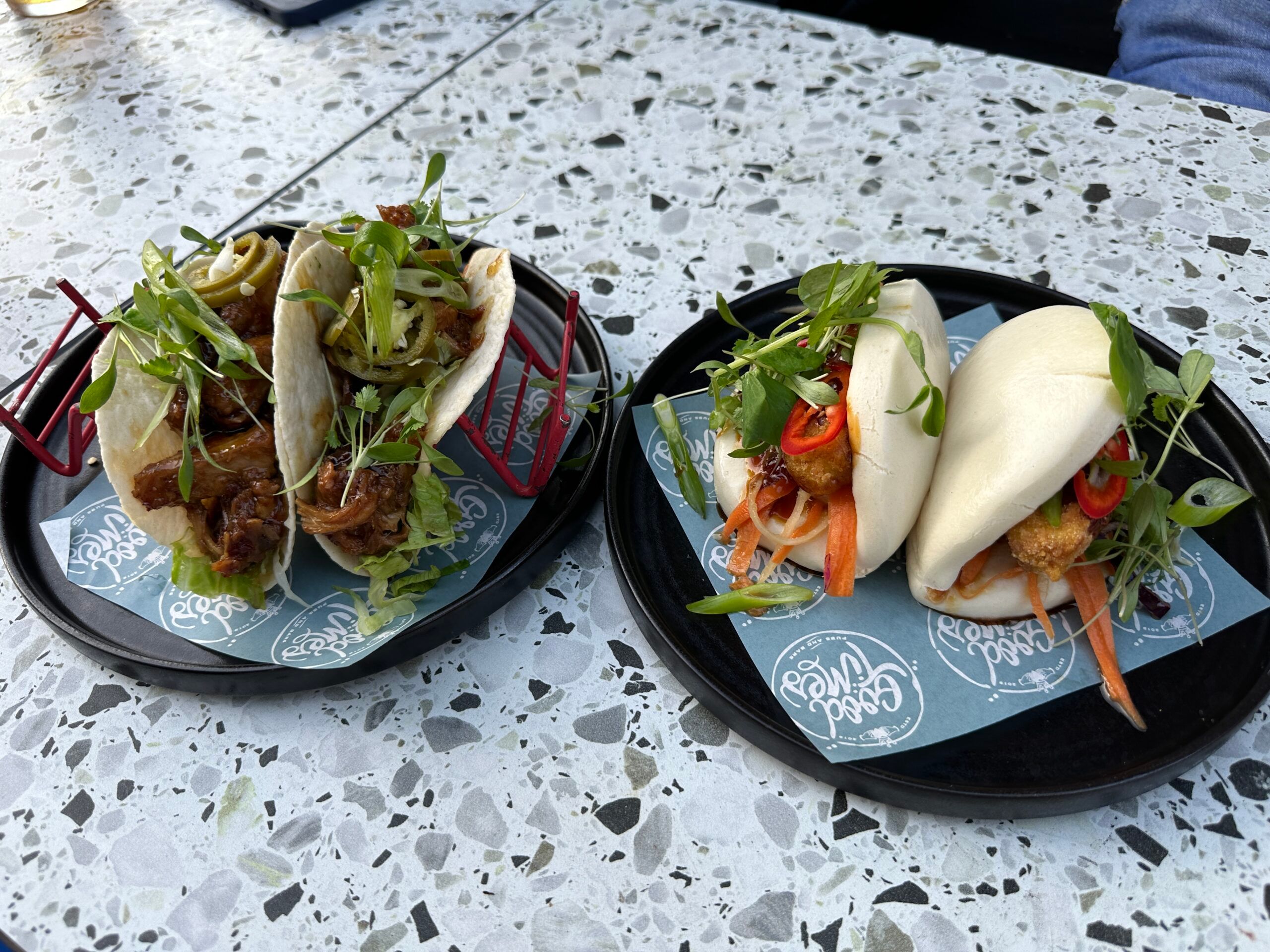 over head shot of the tacos and bao buns served on black plate at the railway Inn. Destination fusion