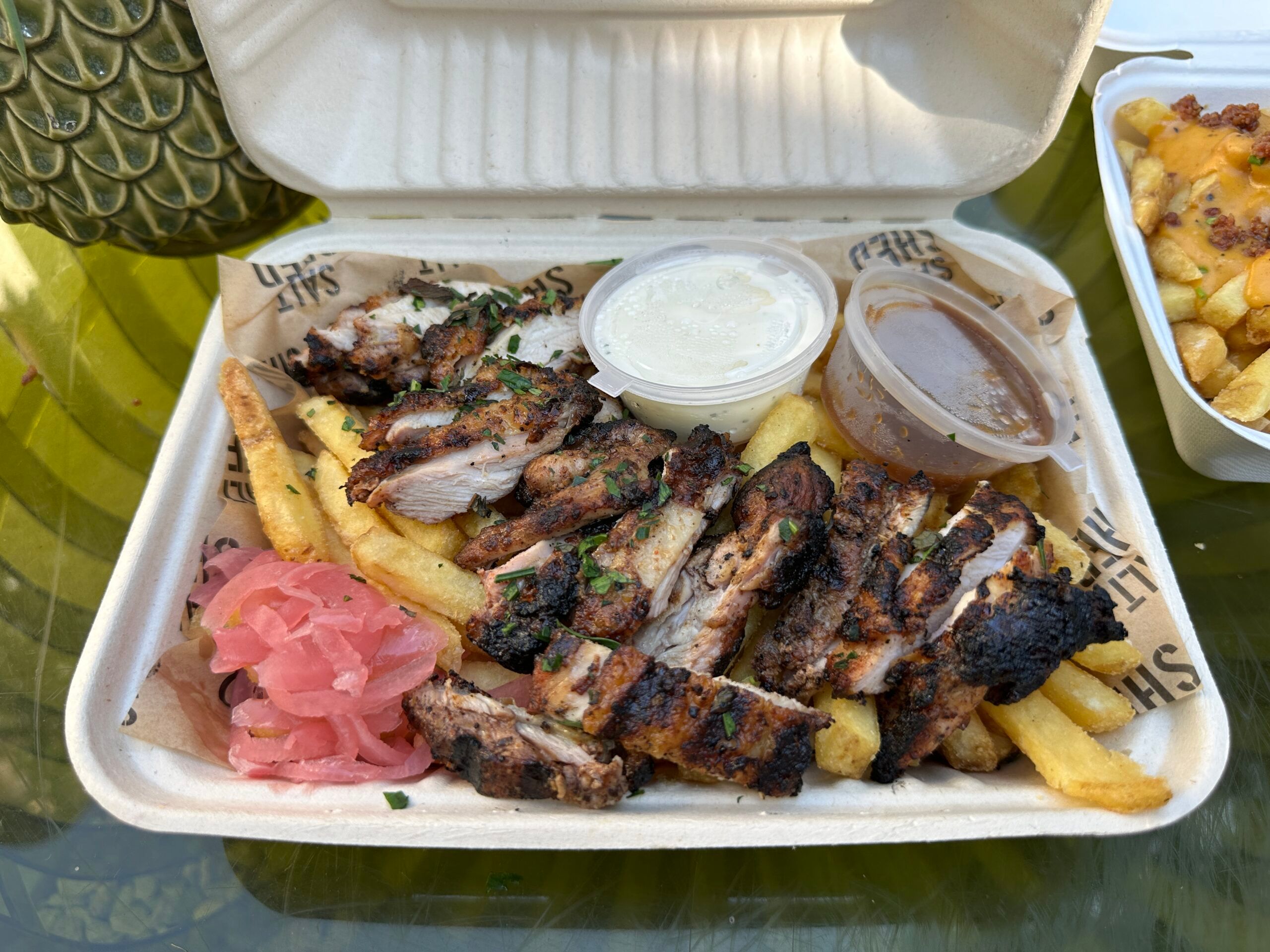 charcoal chicken with fries and sauces inside takeaway box. the salt shed food