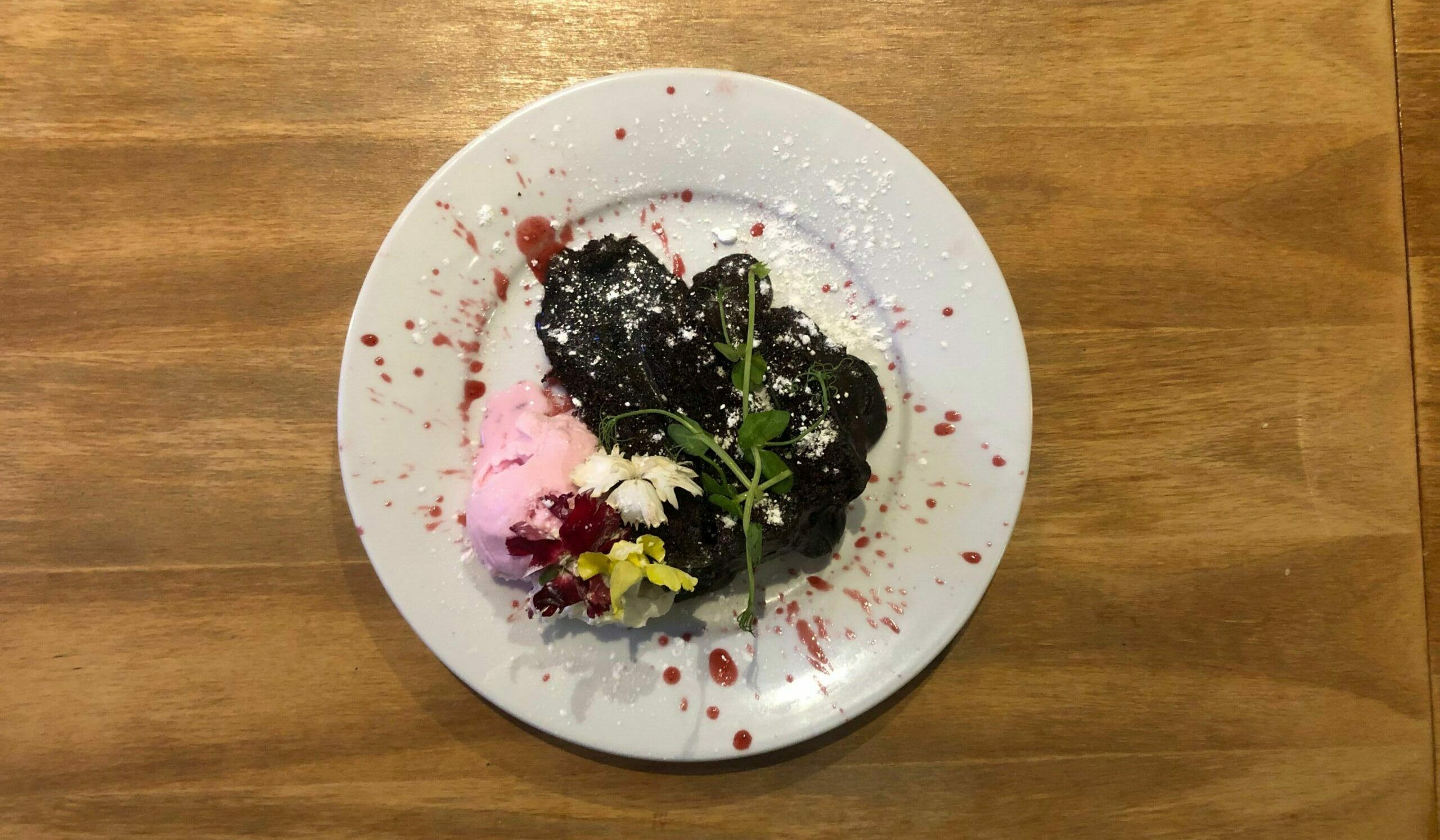 gooey chocolate cake with whipped cream, strawberry ice cream and an arty splattering of strawberry sauce. 