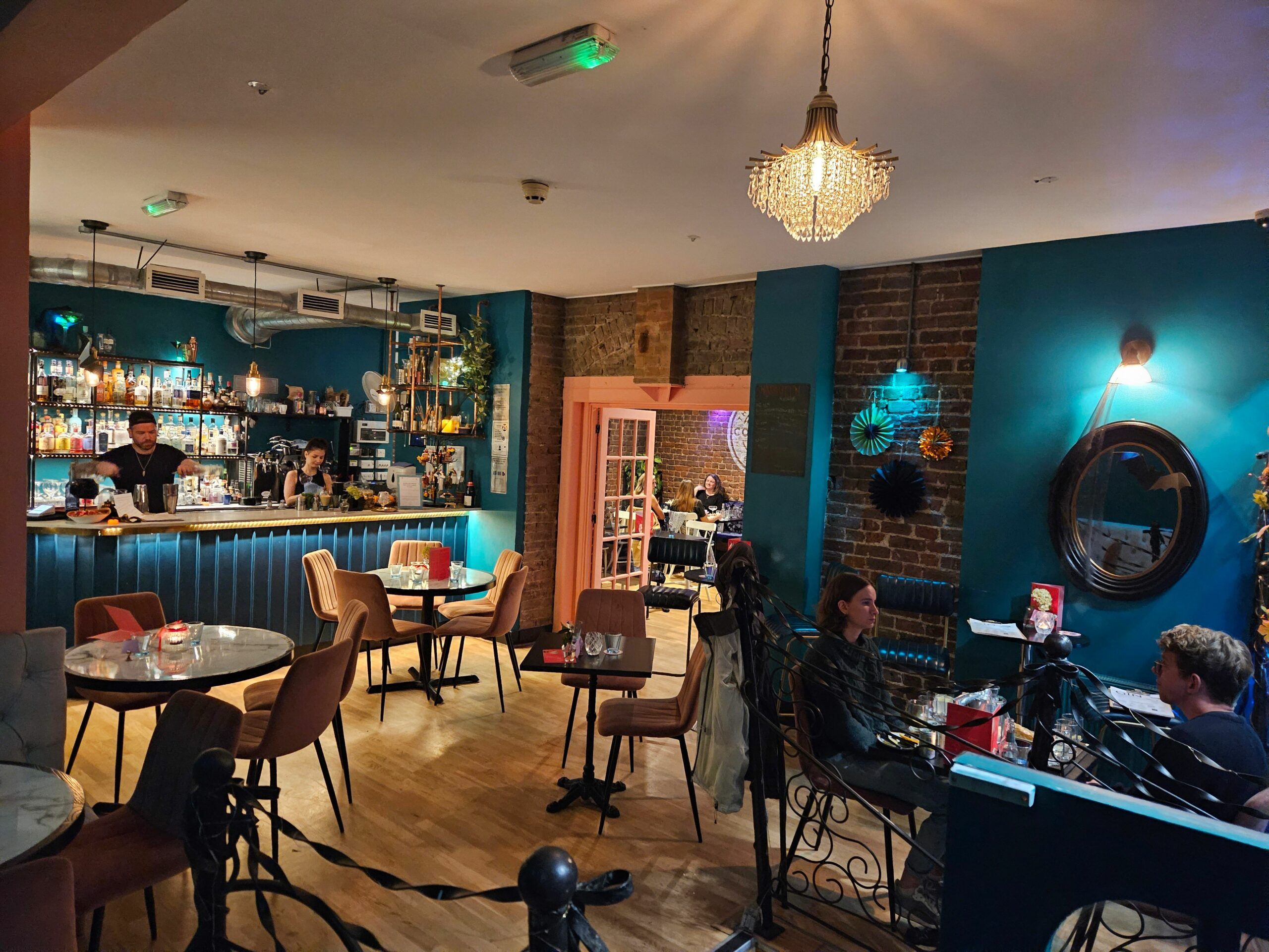 interior shot of Brighton Cocktail Company. Dark blue walls, brown tables and dim lights