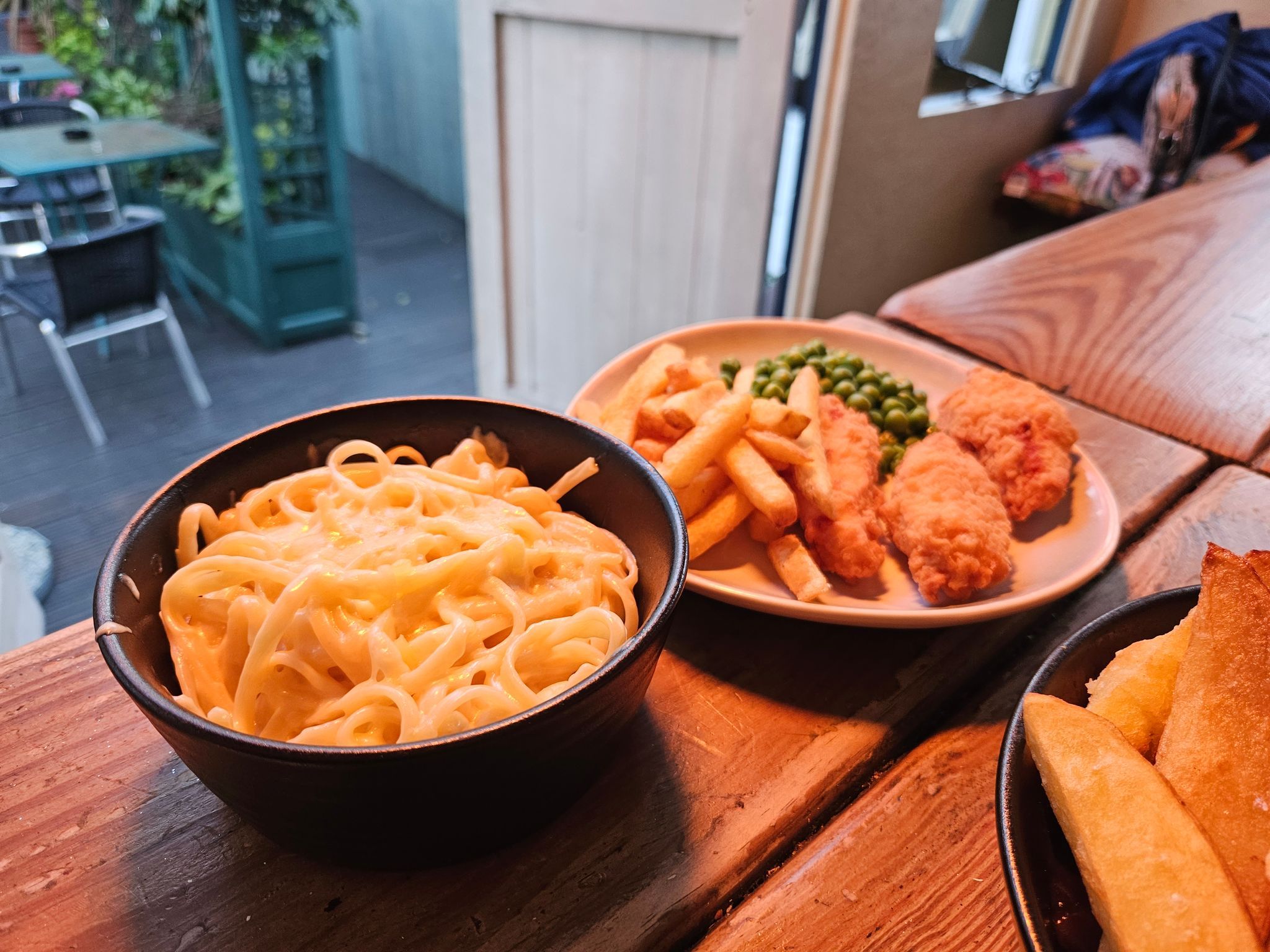 creamy cheese pasta In the black bow and fried chicken and fries on the white table