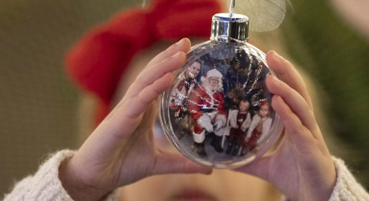Meet Father Christmas at The Royal Pavilion in Brighton. Santas Grotto experience, Christmas with the kids. Pictured a child holding a baubel in Santas Grotto