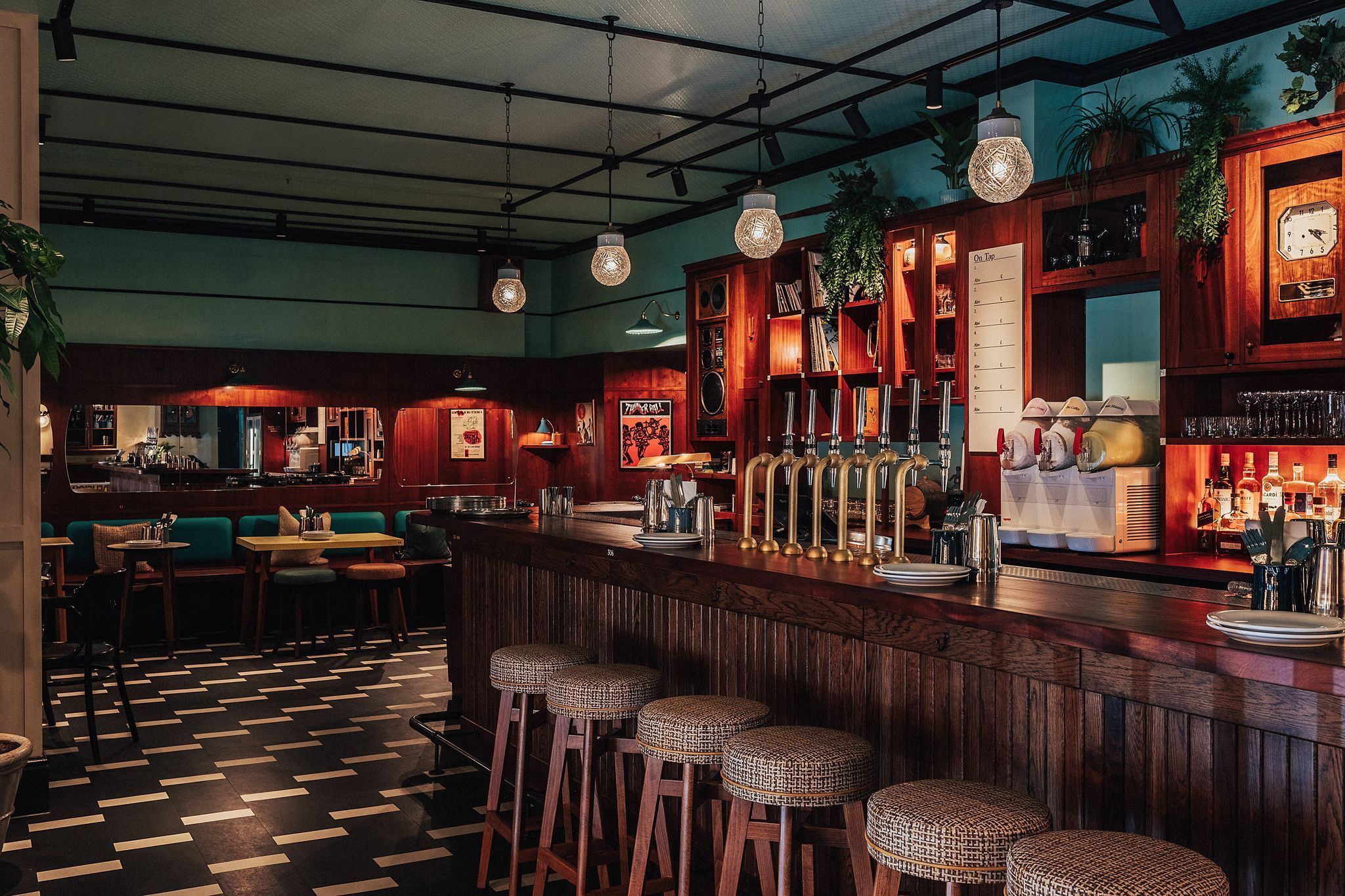 interior shot of the Permit Room Brighton. dim lights, dark green walls, black tiles, brown bar and bar chairs