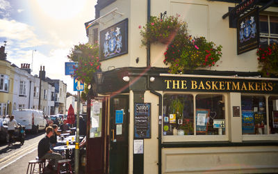 exterior shot of the basketmakers pub on the sunny day, people sitting outside and enjoying their drinks
