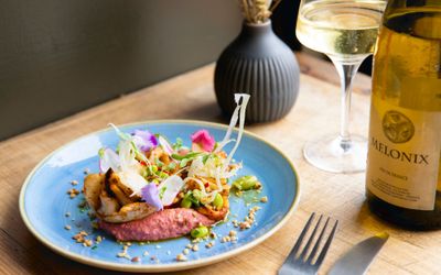 plant based dish served in the light blue plate with glass of white wine