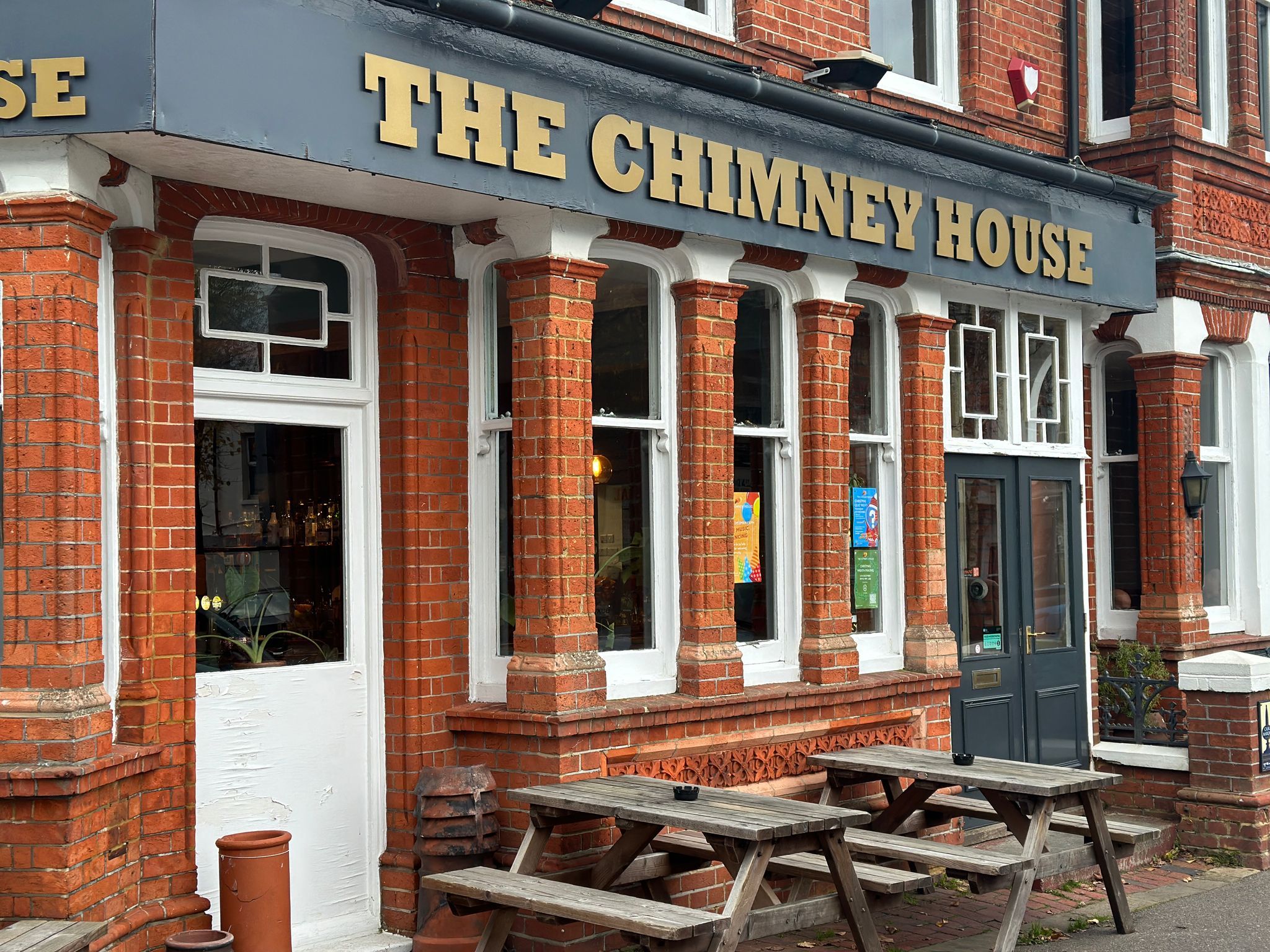 exterior shot of the brown brick building with gray sign with gold letters saying The Chimney House