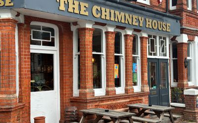 exterior shot of the brown brick building with gray sign with gold letters saying The Chimney House