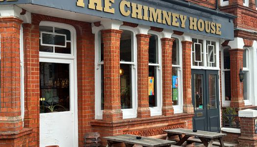 The outside of The Chimney House pub with benches.