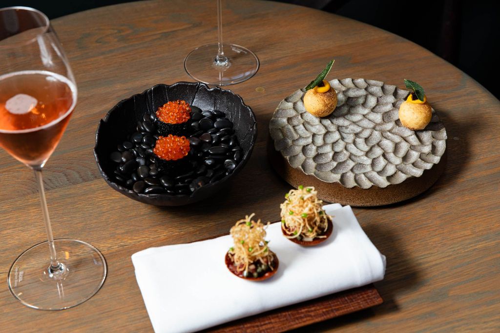 fine dining at Furna, three plates with mini dishes served with red wine