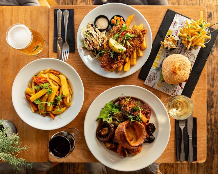 over head shot of four plates with delicious Caribbean food served on the brown table