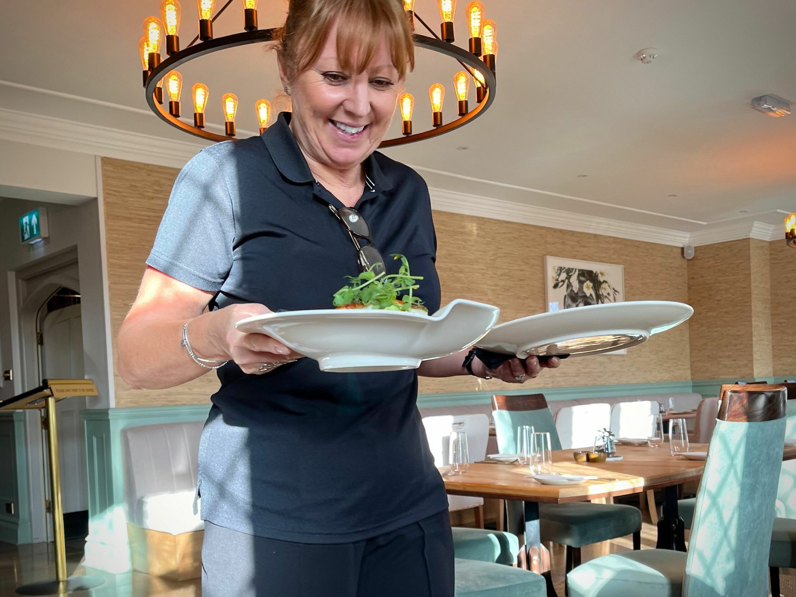 waiter Karen holding two main dishes in white plates