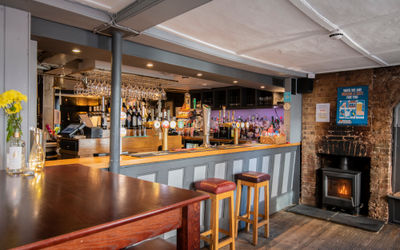 Interiors of The New Inn pub with the bar and seats, with wood burning fire.