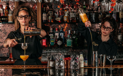 Two mixologists preparing cocktails behind the bar at Blossoms Brighton.