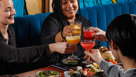 A group of people enjoying happy hour cocktails at food at Blossoms bar in Brighton. Restaurant deals and special offers