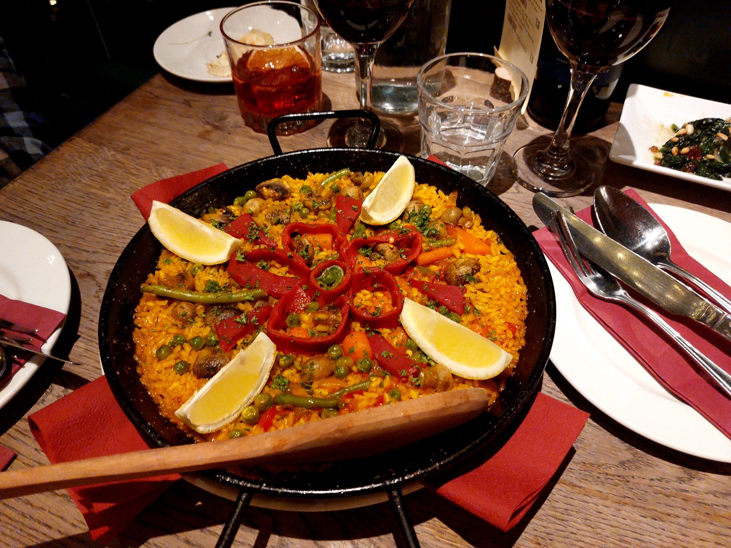 vegan paella served in black pan and with different types of drinks. Vegan tapas experience blog