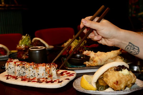 person taking sushi with chopsticks at Blossoms Brighton
