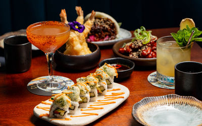 Sushi and cocktails on a wooden table at Blossoms Cocktail Bar in Brighton.