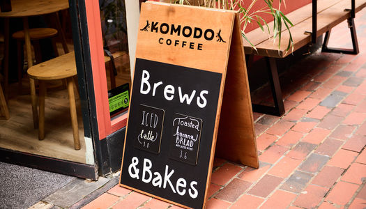 The exterior of Komodo coffee in Brighton. A picture of Komodo coffee A Board, winner of best coffee in Brighton at the 2024 BRAVO Awards