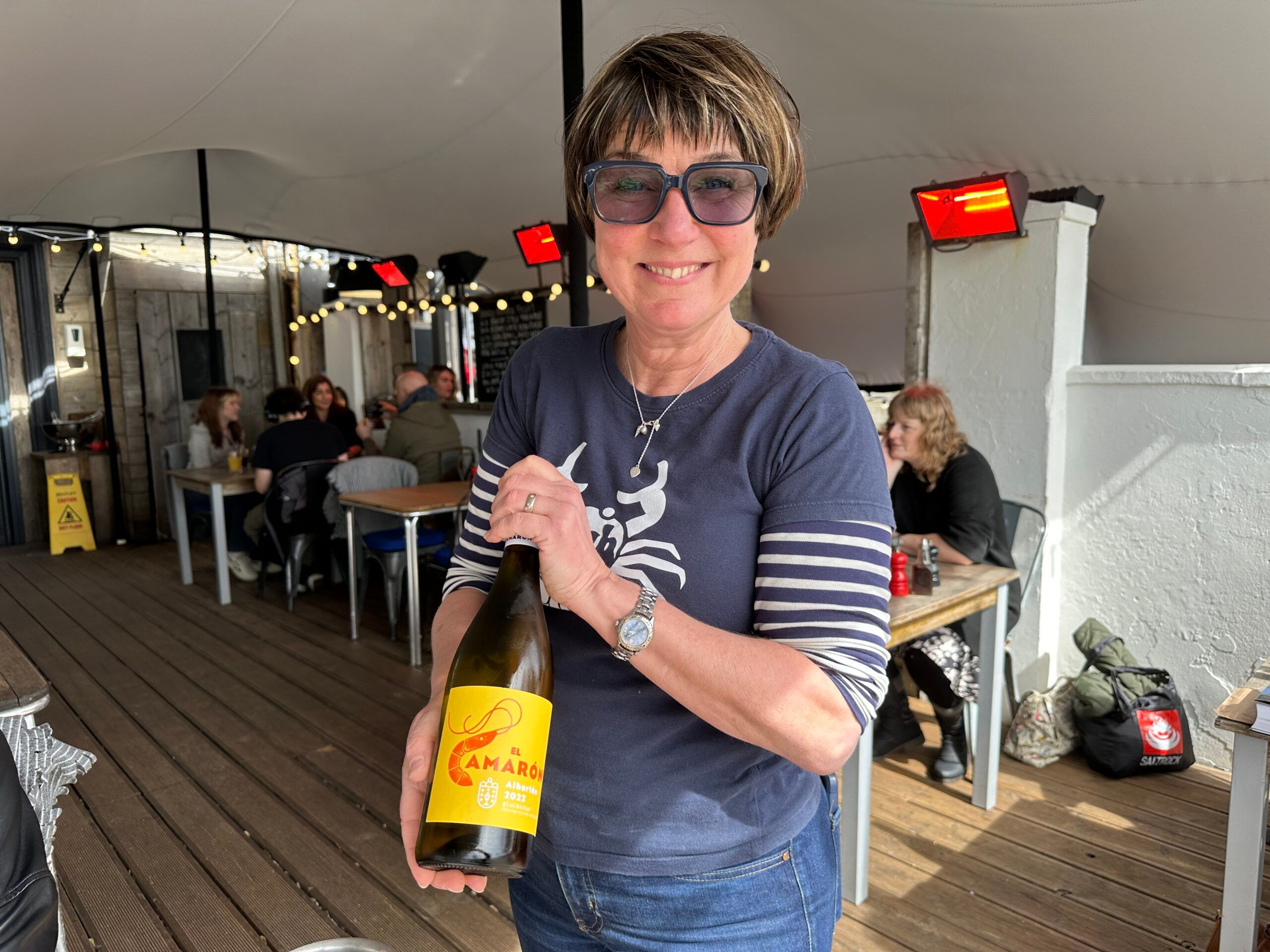 Owner Sarah at Crabshack holding bottle of wine. Beachside dining at the Crabshack Worthing