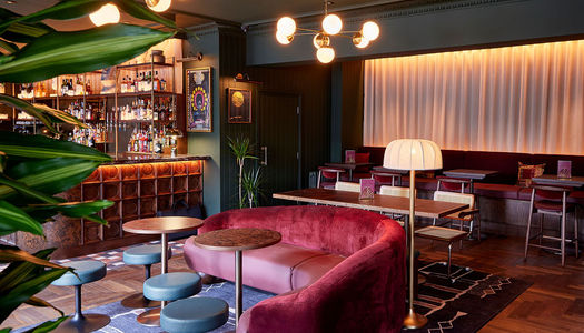 The interior of Tapestry in Hove. Featuring a cocktail bar with glass back mirror and red sofa