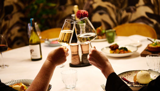 Two glasses of wine with a table of food in the background at Terra Restaurant, Tottington Manor