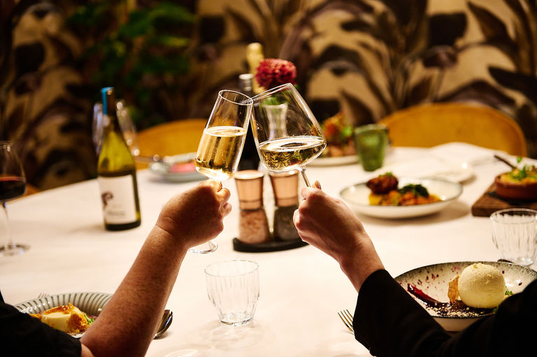 Two glasses of wine with a table of food in the background at Terra Restaurant, Tottington Manor