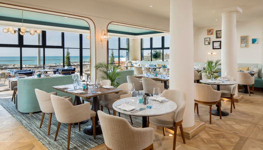 Beautiful seafacing restaurant at White Horses Rottingdean. Lots of natural light, big windows, cream chairs and white tables. Part of our boutique hotels in Brighton guide.