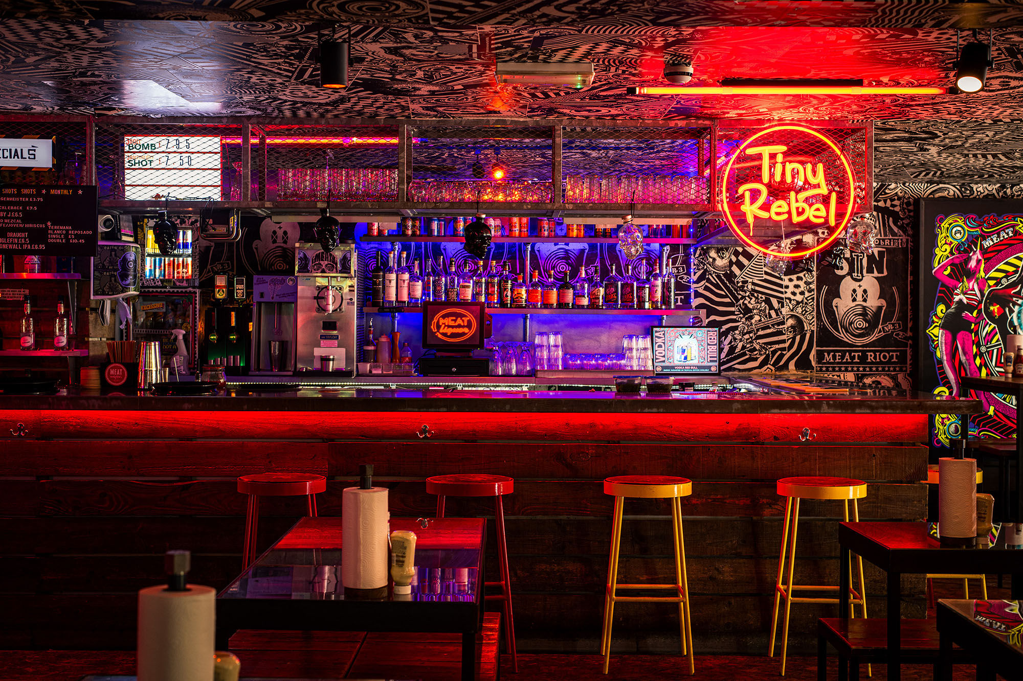 The bar area at MEATliquor with neon lights and red lighting.