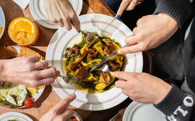 over head shot of few people cutting the dish of the one of the sharing plates