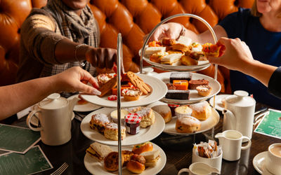 festive afternoon tea at Metropole Bar, hands picking up various cakes from the tray