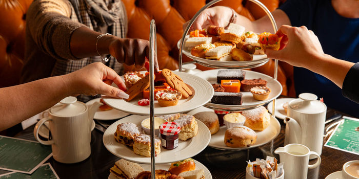 festive afternoon tea at Metropole Bar, hands picking up various cakes from the tray