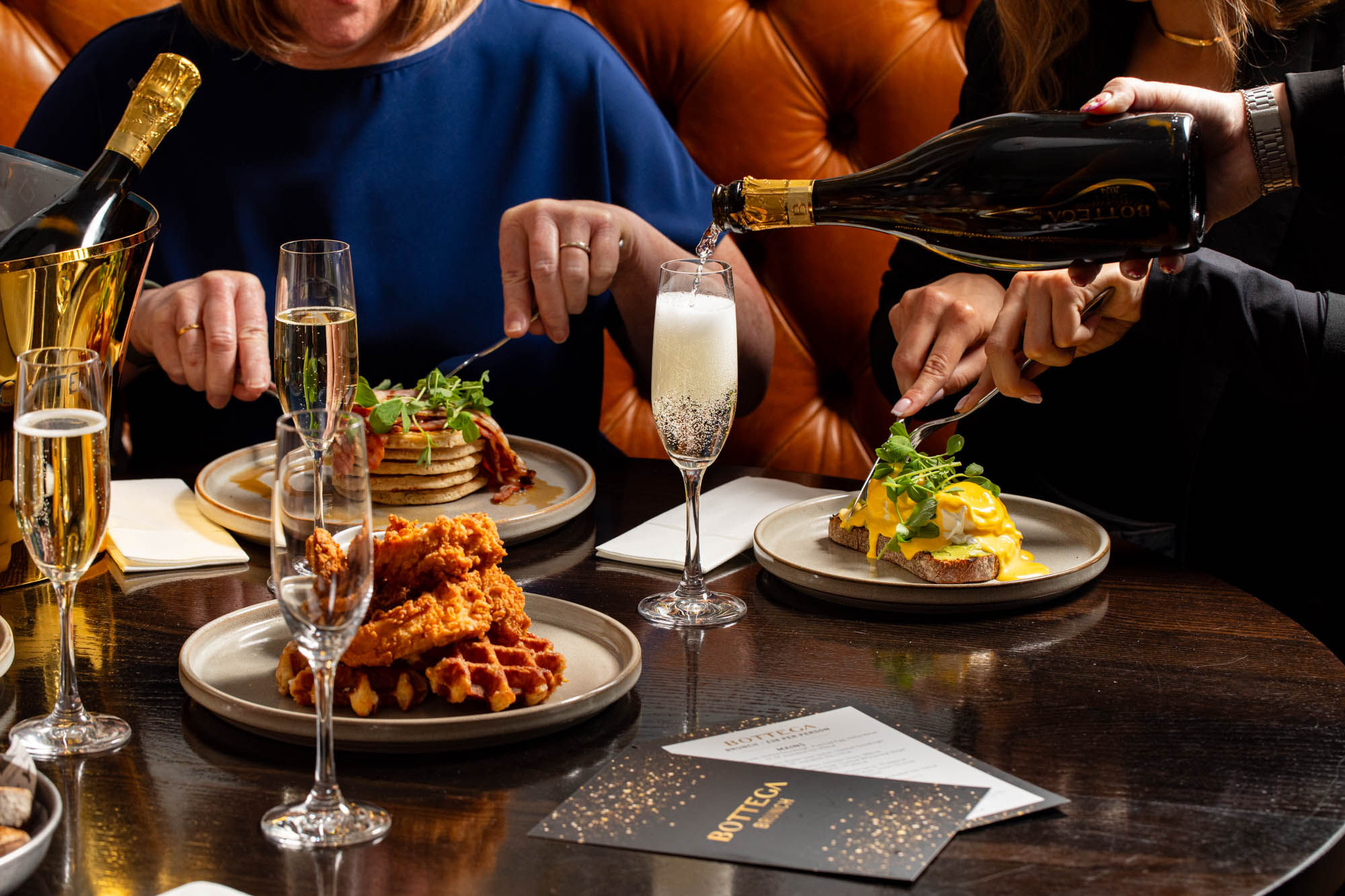 waiter pouring prosecco into glass on the table during brunch at Metropole Bar