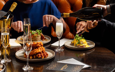 waiter pouring prosecco into glass on the table during brunch at Metropole Bar