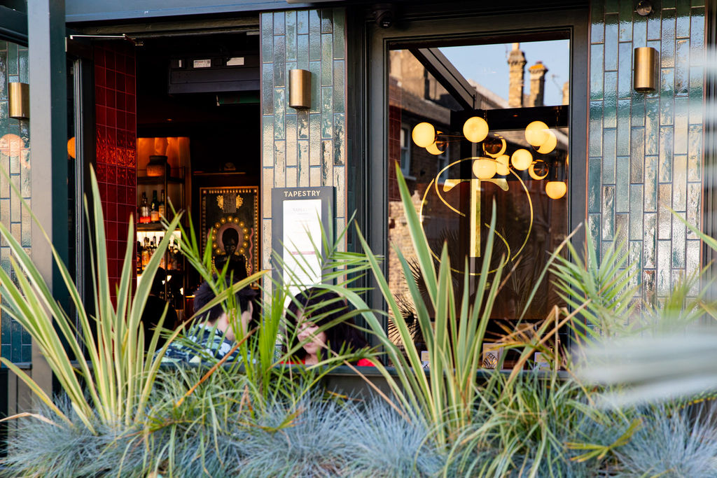 The outside of a bar with plants and people sitting by the door. Photo by: Ellen Richardson