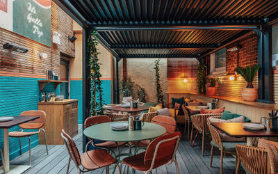 Roof terrace with tables and chairs, foliage and light bulbs giving out ambient light.