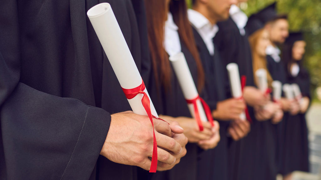 students with their graduation gowns and diplomas in Brighton. The image celebrates graduation day in Brighton and Hove and recommends where students from Brighton and Sussex university can go and celebrate. Pubs, restaurants and cafes for graduations dinners with families concentrating on the brighton and Hove area.