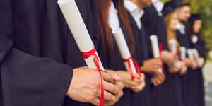 students with their graduation gowns and diplomas in Brighton. The image celebrates graduation day in Brighton and Hove and recommends where students from Brighton and Sussex university can go and celebrate. Pubs, restaurants and cafes for graduations dinners with families concentrating on the brighton and Hove area.