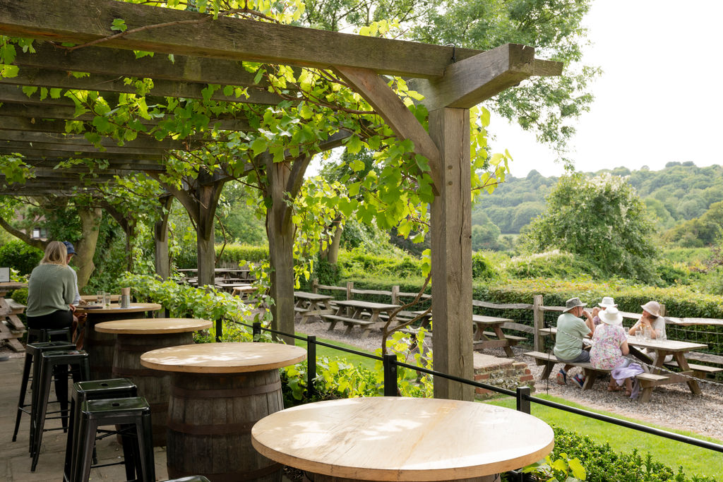 Lush alfresco area with a pergola and seating and countryside views.