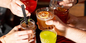 4 cocktails being cheersed by 4 faceless people