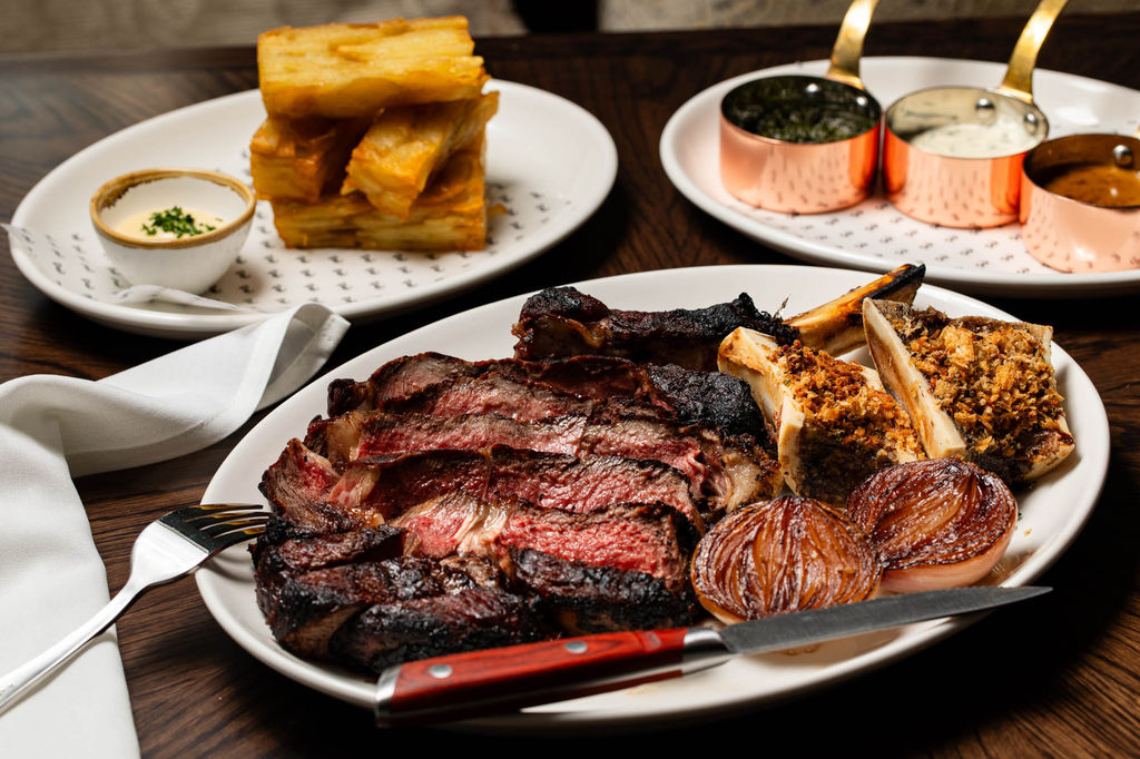 Standout steaks at Pearly Cow restaurant in Brighton include: 45-day salt-aged 8oz fillet, 12oz ribeye, and 36oz côte de boeuf for sharing, cooked over open fire. Accompaniments: beef-fat chips, glazed onions, bone marrow butter, sauces (peppercorn, chimichurri, Béarnaise)