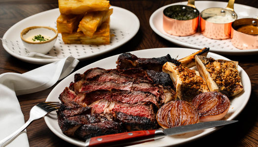 Standout steaks at Pearly Cow restaurant in Brighton include: 45-day salt-aged 8oz fillet, 12oz ribeye, and 36oz côte de boeuf for sharing, cooked over open fire. Accompaniments: beef-fat chips, glazed onions, bone marrow butter, sauces (peppercorn, chimichurri, Béarnaise)